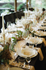 table set for a wedding reception; table in restaurant; wedding table setting; long table with decoration
