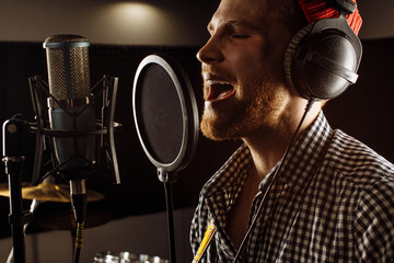 handsome caucasian guy in recording studio. young man professional singer preparing before music...