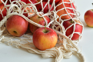 Mesh textile bag full of red apples. Healthy food and zero waste concept.