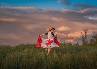 Boy running through a field holding a Canadian Flag, Bedford, Halifax, Nova Scotia, Canada