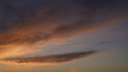 Fototapeta premium A beautiful evening blue sky at sunset with flaming bright light clouds. Warm evening.