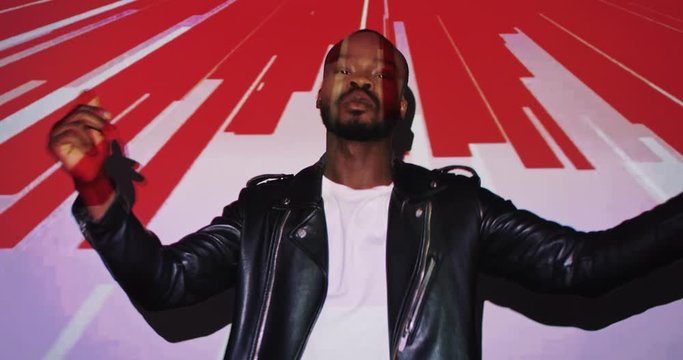 Portrait of African American young stylish man posing to camera and dancing cheerfully in black and red projections in patterns and curves in digital art videoshoot. Projected lines colors and graphic