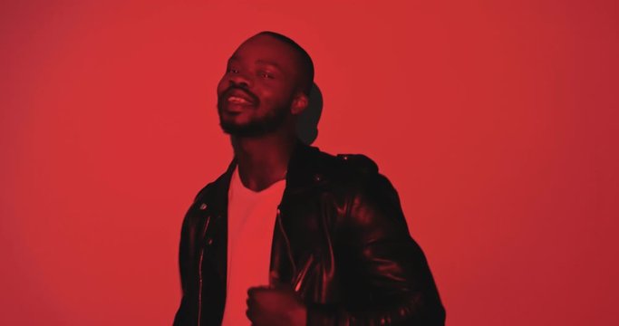 Portrait of African American young stylish handsome man posing to camera like model in black and red projections in patterns and curves in digital art videoshoot. Projected lines, colors and graphic.
