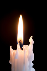 Candleflame on a lit candle.  White candle burning, isolated on a dark background