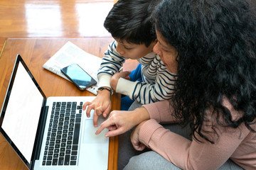 Executive woman working from home on her computer while sharing moments with her son