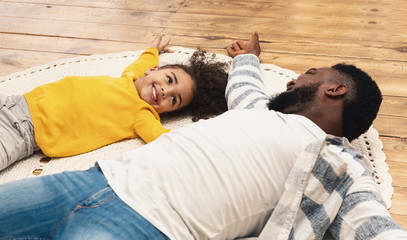 Smiling african american father and daughter staying home