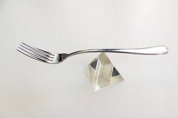 Silver fork  on glass pyramid white background balance diet concept