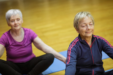 coppia di anziane si dedica allo yoga in palestra