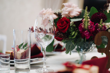 rose and wine glasses; elegant table setting; wedding table setting in red colors; сhristmas table setting
