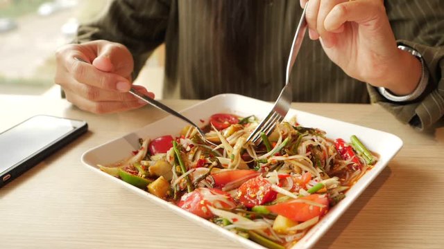 Slow-motion video of a Thai woman using a spoon to scoop the papaya salad to eat. Somtum is the national food of Thailand. Concepts of healthy food.