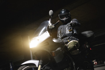 Motor biker on a motorcycle is showing at screen by his index finger.