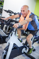 Uomo anziano  si allena in una palestra con lo spinning