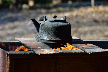 Old kettle on the grill. Tea in nature. Kettle on the fire.