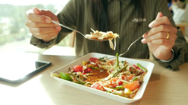 Slow-motion video of a Thai woman using a spoon to scoop the papaya salad to eat. Somtum is the national food of Thailand. Concepts of healthy food.