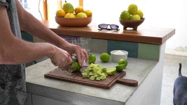 Close up of man hand preparing recipe for &ldquo;caipirinha&rdquo; drink with lime, sugar, ice and &ldquo;cachaca&rdquo; on kitchen countertop. The cacha&ccedil;a of Brazil is made of sugar cane. 4K