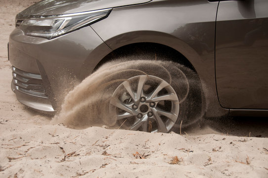 Car wheels on a sea beach sand. Close-up of car wheel on sandy dunes in countryside..Car stuck in the sand. Spinning wheel of a car stuck in the sand.