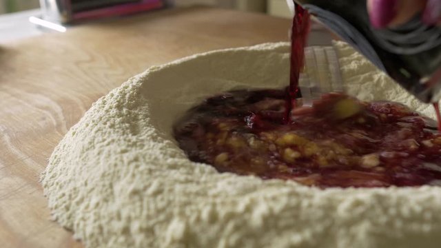 Mixing egg and red wine with fork in circle of flour, Close Up, Home Cooking