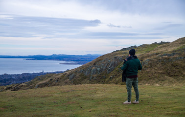 young man standing on mazing yellow and green mountain landscape watching the landscape and taking...