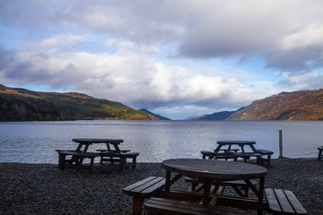 beautiful views of a lake with eating tables in the front and mountains in the background