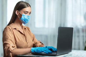 Woman wearing face mask and working on laptop