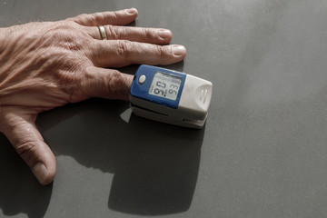Misuratore di ossigeno da dito su una mano, su sfondo grigio