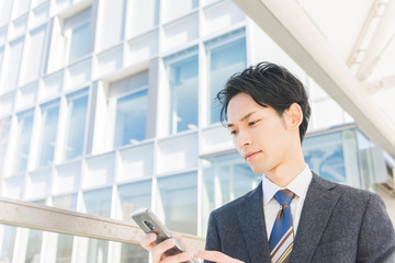 Fototapeta premium スマートフォンを手に持つビジネスマン