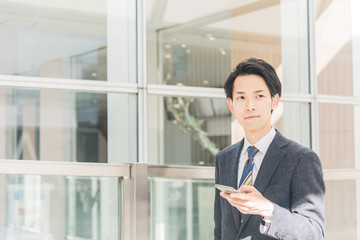 Fototapeta premium スマートフォンを手に持つビジネスマン