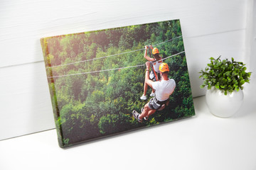 Canvas print on white table. Photo with gallery wrap method of canvas stretching on stretcher bar. Color photography with image of people on zip line. Interior decor