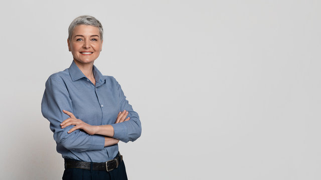 Portrait Of Mature Businesswoman Posing With Folded Arms Over Light Background