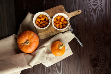 Baked pumpkin in white ceramic bowl on wooden background