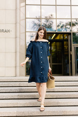 Beautiful young lady with long healthy hair and cute dress walking on the street. Hot summer evening. Sunset. Lifestyle concept. 