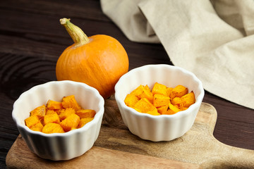 Baked pumpkin in white ceramic bowl on wooden background