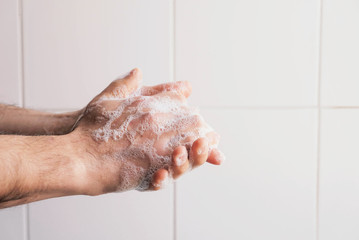 Fototapeta premium Washing hands concept. Man cleaning his hands using liquid disinfectant soap and water in bathroom, close up. Personal hygiene, health care and coronavirus prevention.