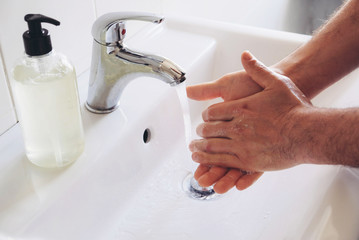 Washing hands concept. Man cleaning his hands using liquid disinfectant soap and water in bathroom, close up. Personal hygiene, health care and coronavirus prevention.