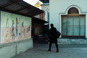  a woman walks past children's drawings