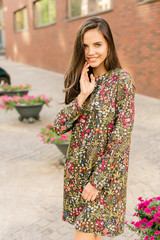 Beautiful portrait of brunette young woman wearing dress with flower pattern trendy dress and...