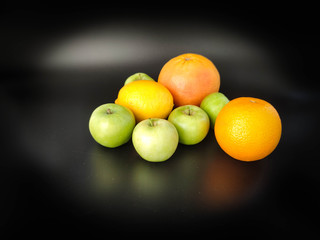 Whole fruits green apples, orange, grapefruit and lemon on black background. Concept - vegetarian and healthy food to improve the immunity Stock photo.