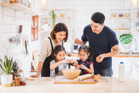 Asian Family Enjoy Playing And Cooking Food In Kitchen At Home