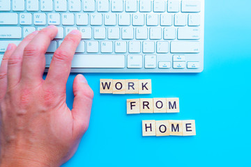 Blurred background, wooden boards, placing computer with text WORK FROM HOME.  The company allows employees to work from home to avoid viruses.