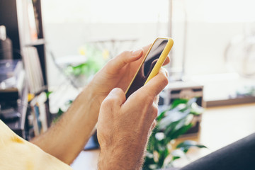 Close-up of man hands holding cell  phone in yellow case and using internet, doing calls, checking...
