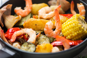 pan with fried vegetables, shrimp and squid with spices