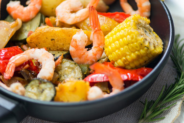 pan with fried vegetables, shrimp and squid with spices
