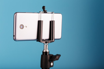 Smartphone on a tripod as a photo-video camera on a blue background. Record videos and photos for your blog.