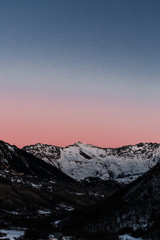 Obraz premium A beautiful sunset sky with shades of fading pink and blue over a snowy mountain in winter