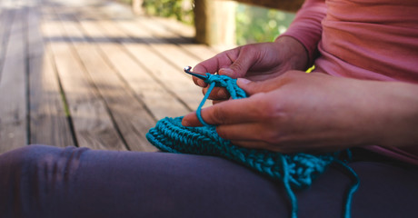 Obraz na płótnie Canvas Woman crochets from thick blue yarn during quarantin.