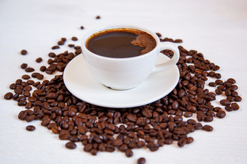 White cup of coffee stands on coffee beans
