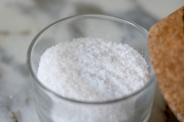 Sea salt in a glass pot over a marble countertop close up