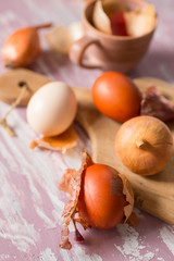 Eggs and onions on a rustic cutting board. Easter eggs dyed in natural dye - onion skins