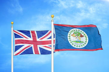 United Kingdom and Belize two flags on flagpoles and blue cloudy sky