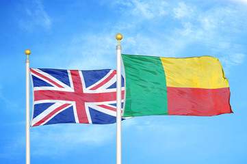 United Kingdom and Benin two flags on flagpoles and blue cloudy sky